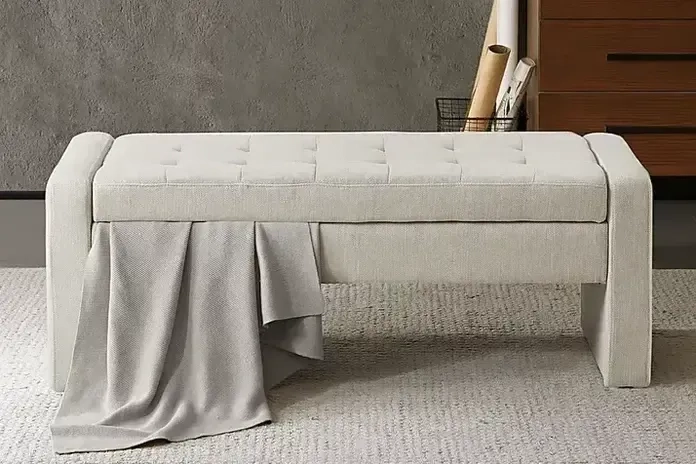 a beige storage bench with a blanket on it 