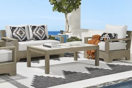a white and brown loveseat set with a center table near the water