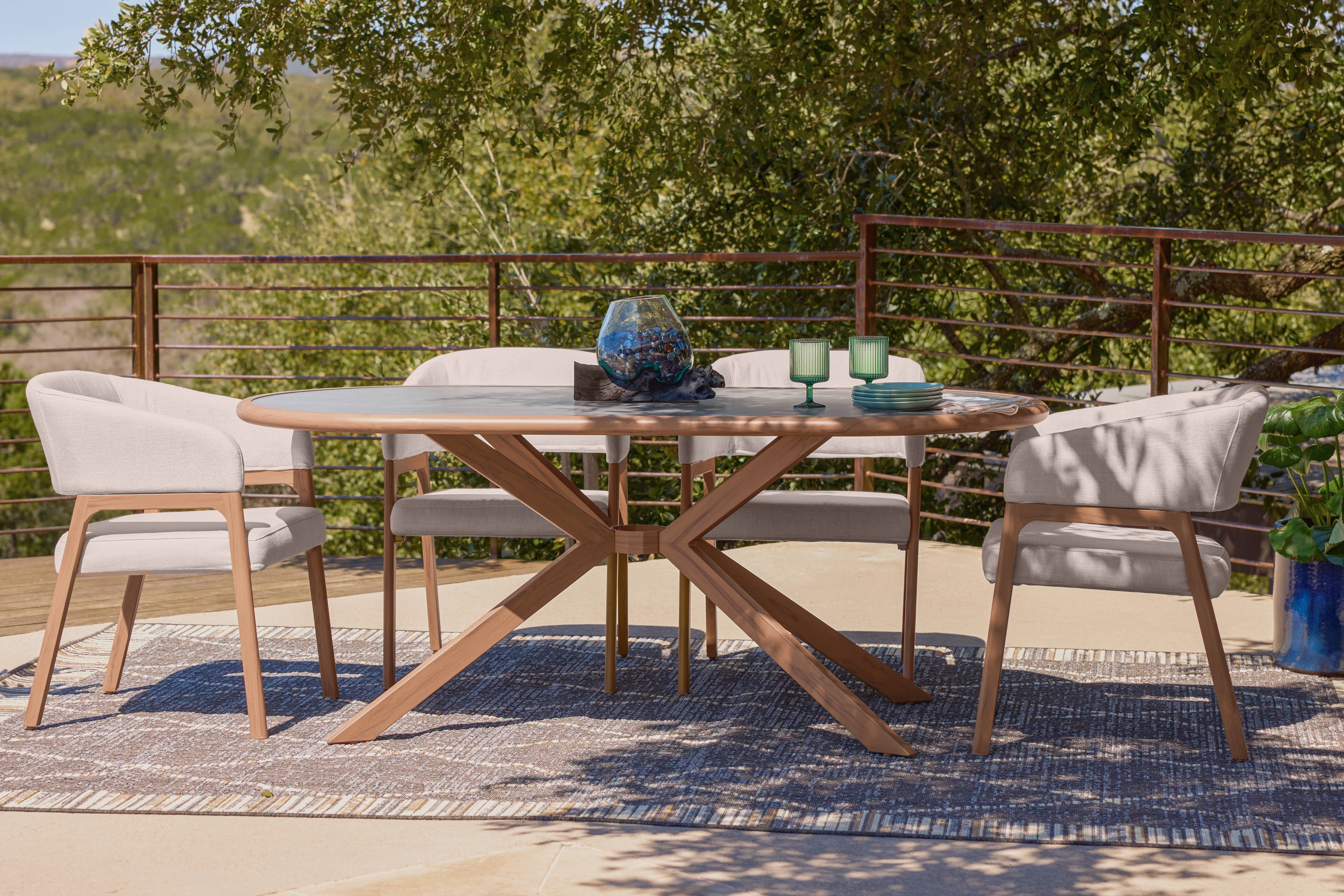 Outdoor dining set with a round table, chairs, and rug.
