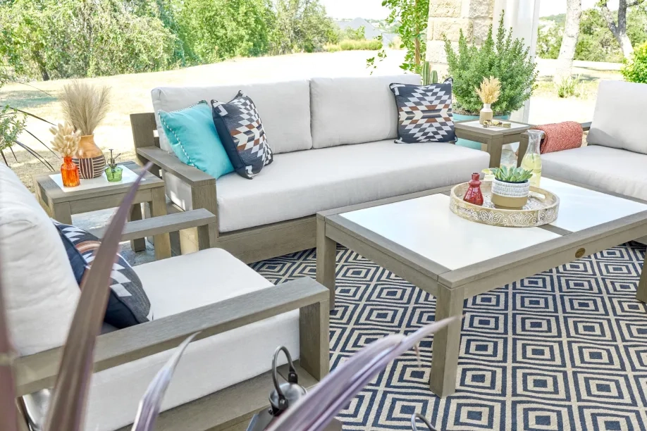 Outdoor patio set with white cushions, geometric rug, and decorative pillows