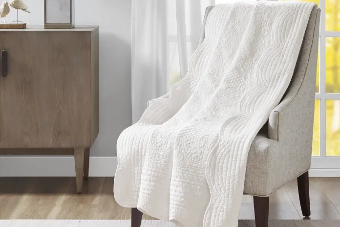 grey chair with blanket over it 