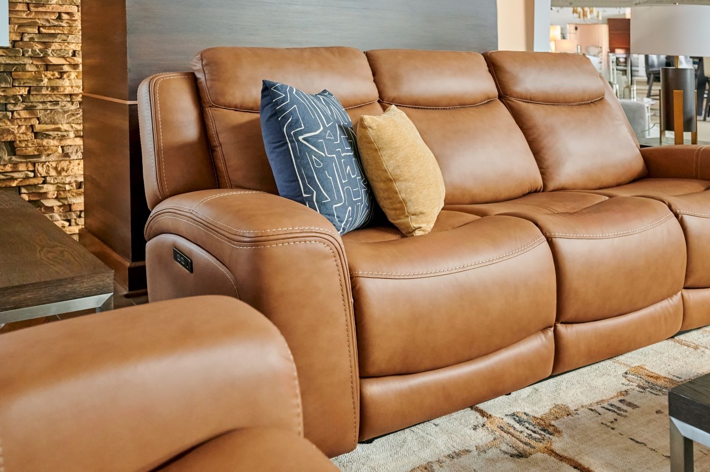 Brown leather reclining sofa with two decorative pillows.

