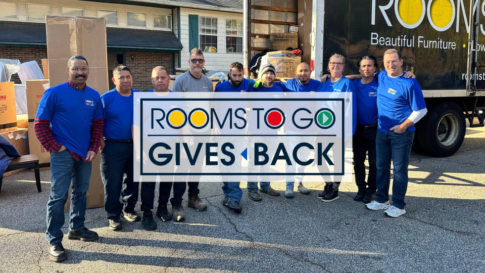 Rooms To Go Gives Back. Group of people in blue shirts standing in front of a truck.
