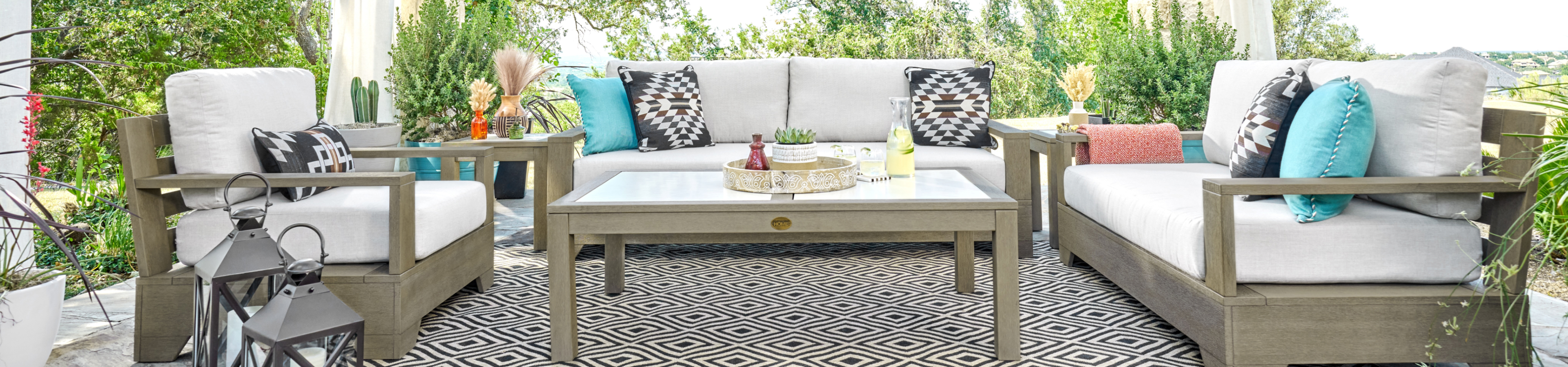 Outdoor patio set with white cushions, colorful pillows, and a patterned rug