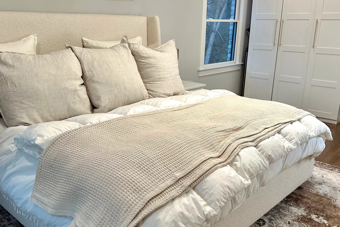 white bedroom with tan pillows and blanket