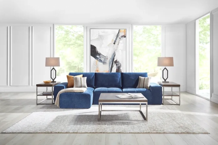 Modern living room with blue sofa, end tables, and abstract art