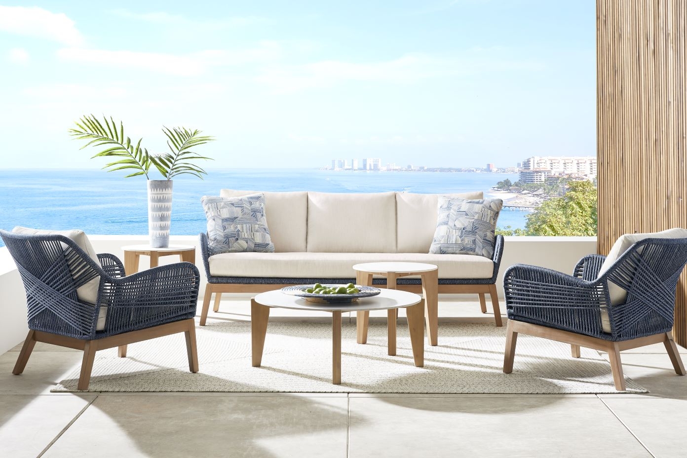 Outdoor furniture set with a sofa, two chairs, and two tables.
