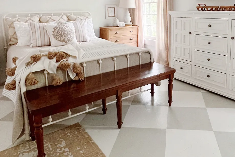 white bedframe with a brown accent bench in front