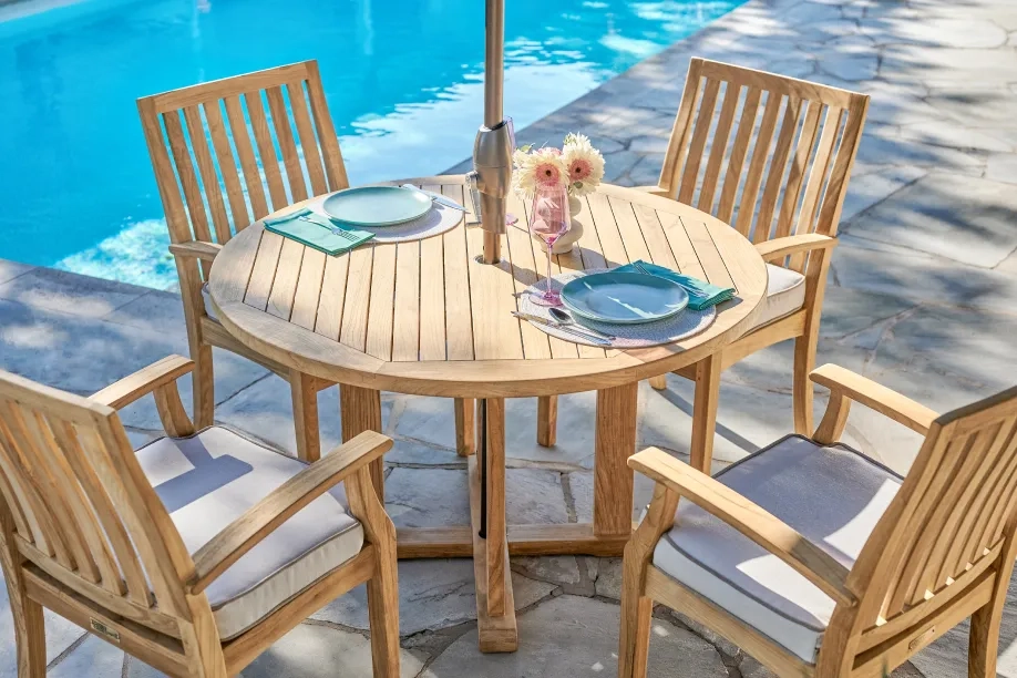 wooden dining table and chairs next to the pool