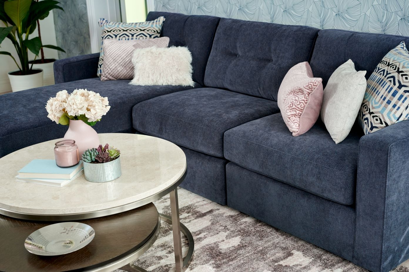 A navy blue sectional sofa with decorative pillows and a round coffee table.
