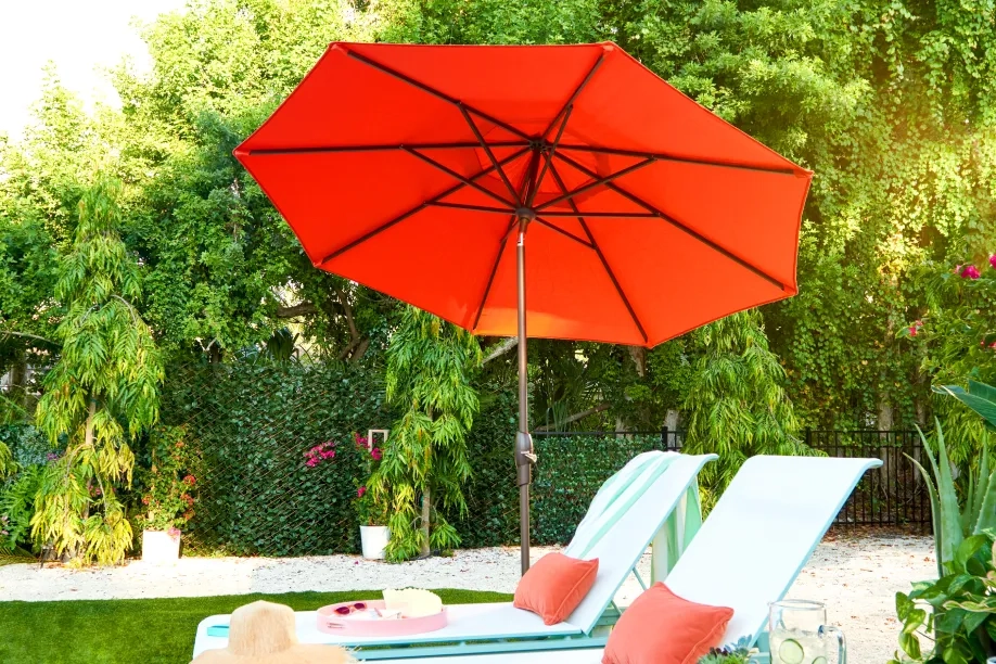 red tilting umbrella next to two chaise loungers