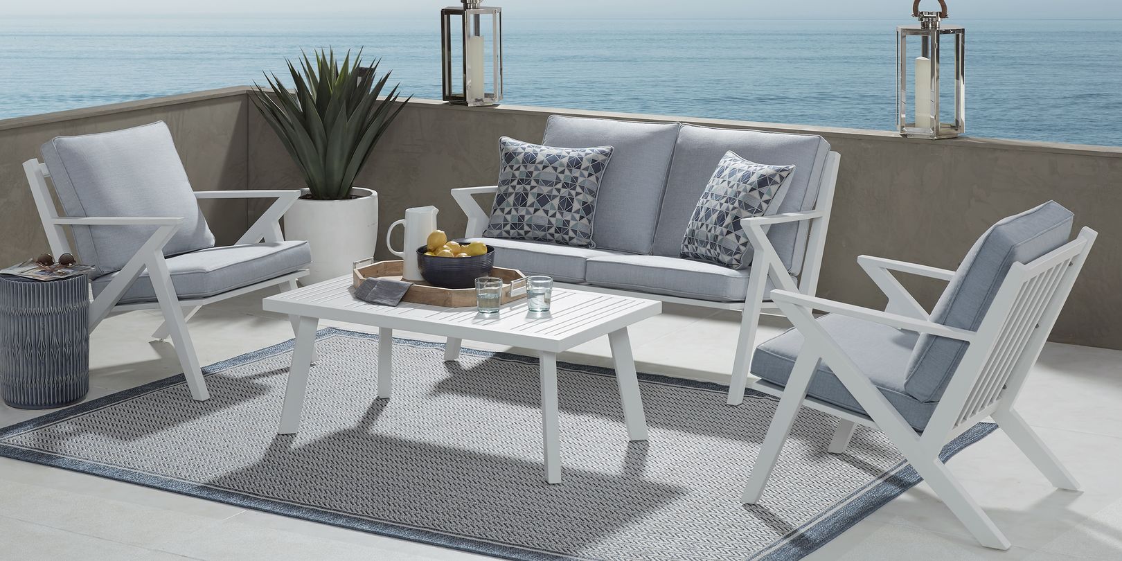 Photo of a white patio seating set with blue cushions and a table