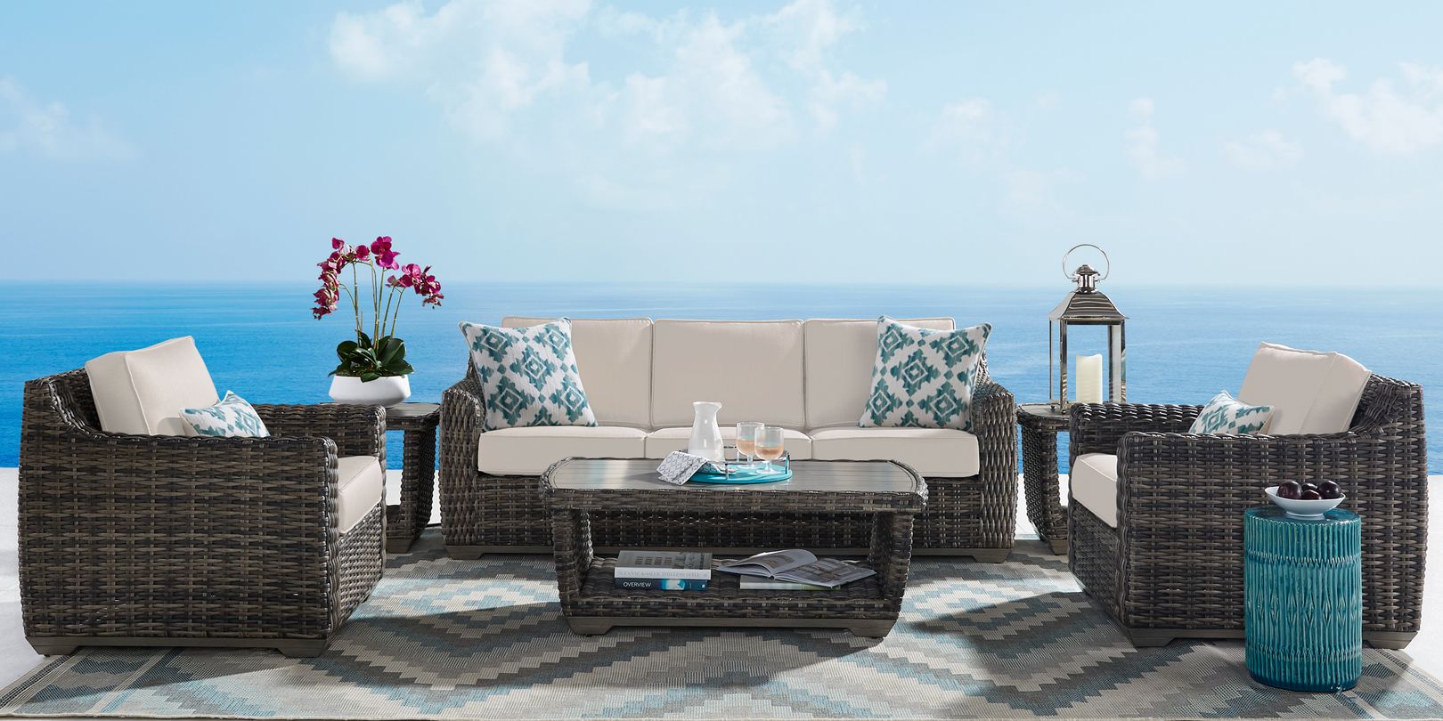 Photo of dark brown wicker patio seating set with tan cushions and matching tables