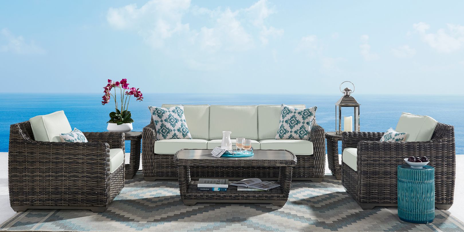 Photo of a dark brown wicker sofa and pair of chairs with matching coffee and end tables