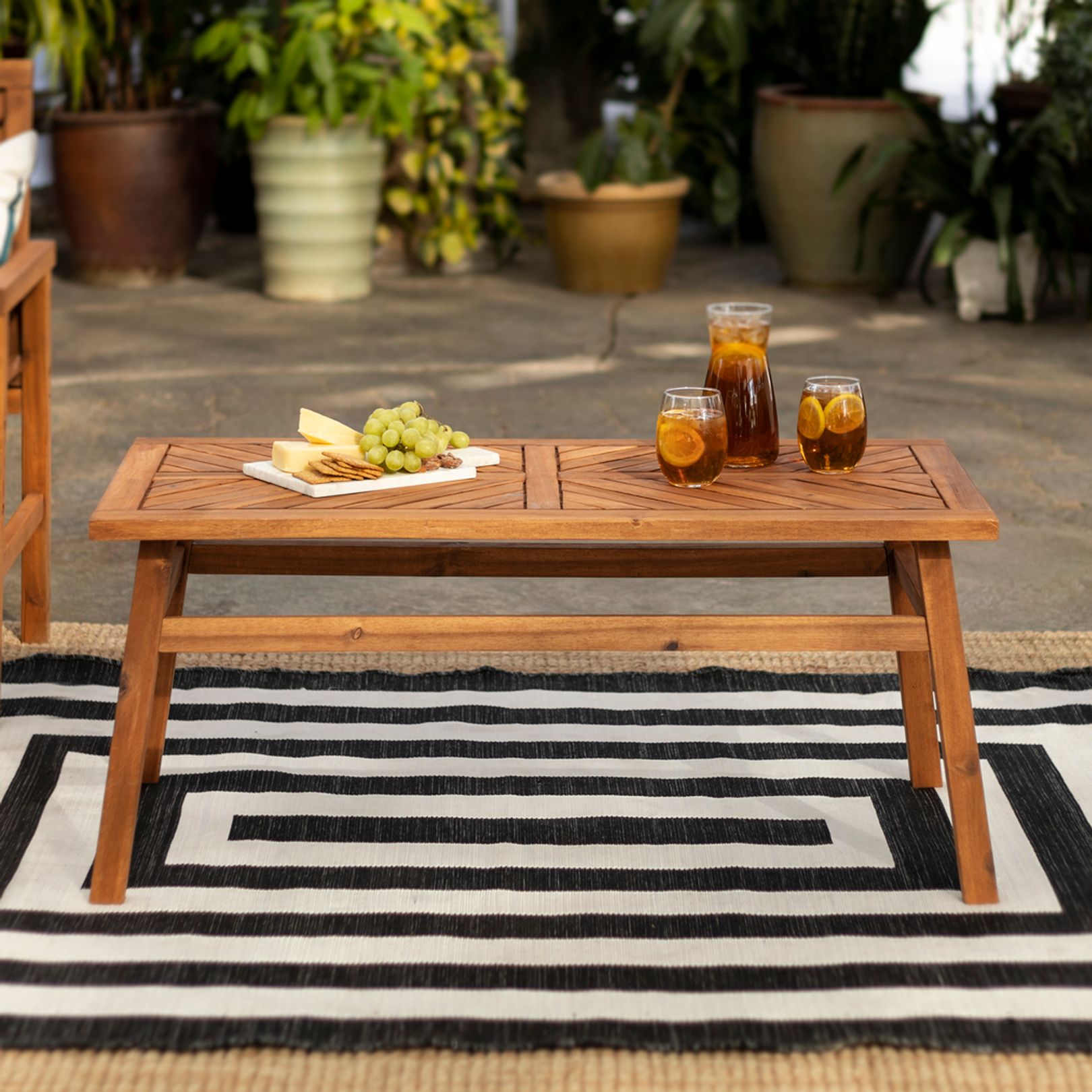 Photo of teak patio coffee table atop a black and white patterned rug