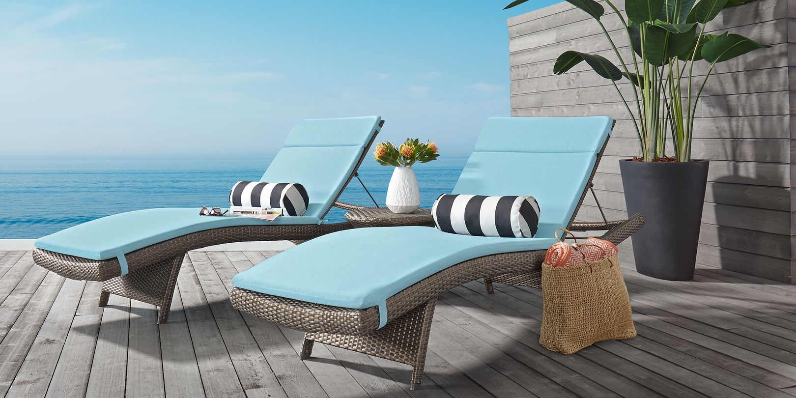 Photo of a pair of brown wicker patio chaises with seafoam cushions