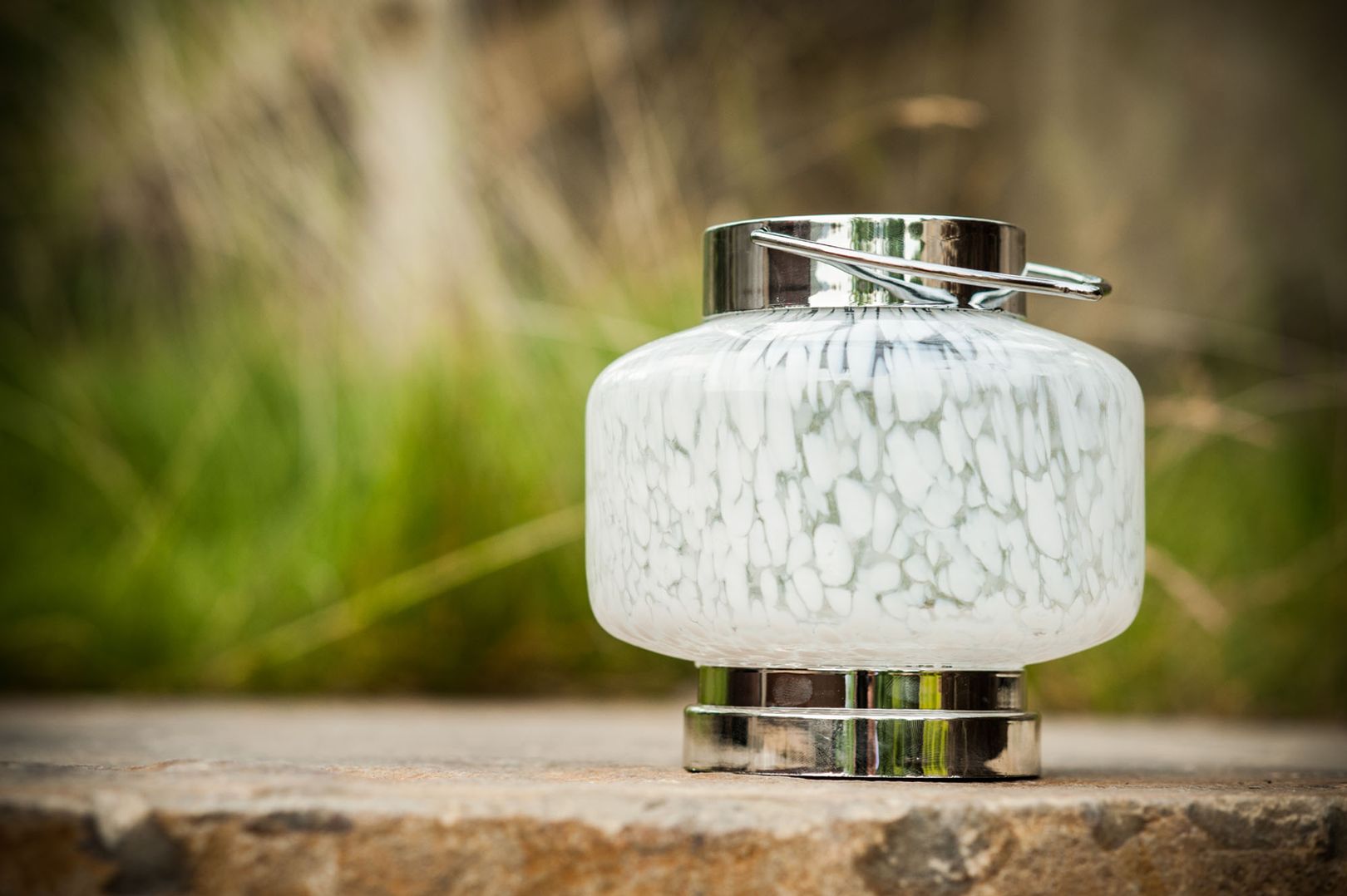 Photo of white and chrome solar lantern sitting atop a stone wall