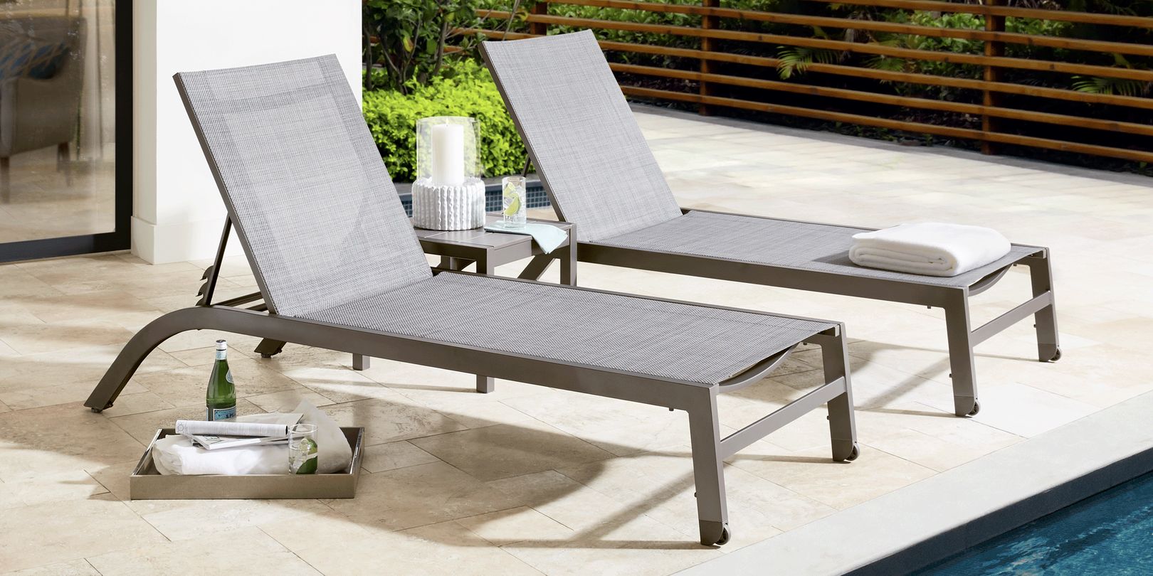 photo of two metal chaise lounges and a serving tray near a swimming pool