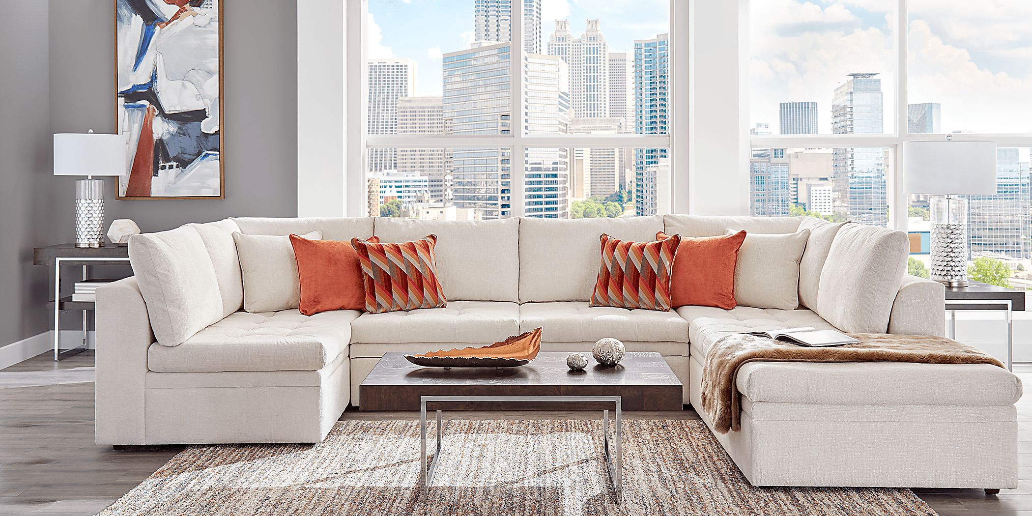 WHite and blue pillows accent a white linen couch placed in a white and  gray living room in front of a glass-paneled door f…