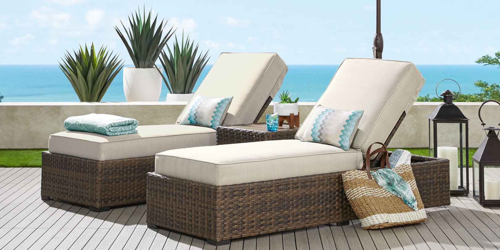 Photo of a pair of brown wicker chaise lounges with a matching end table on a patio