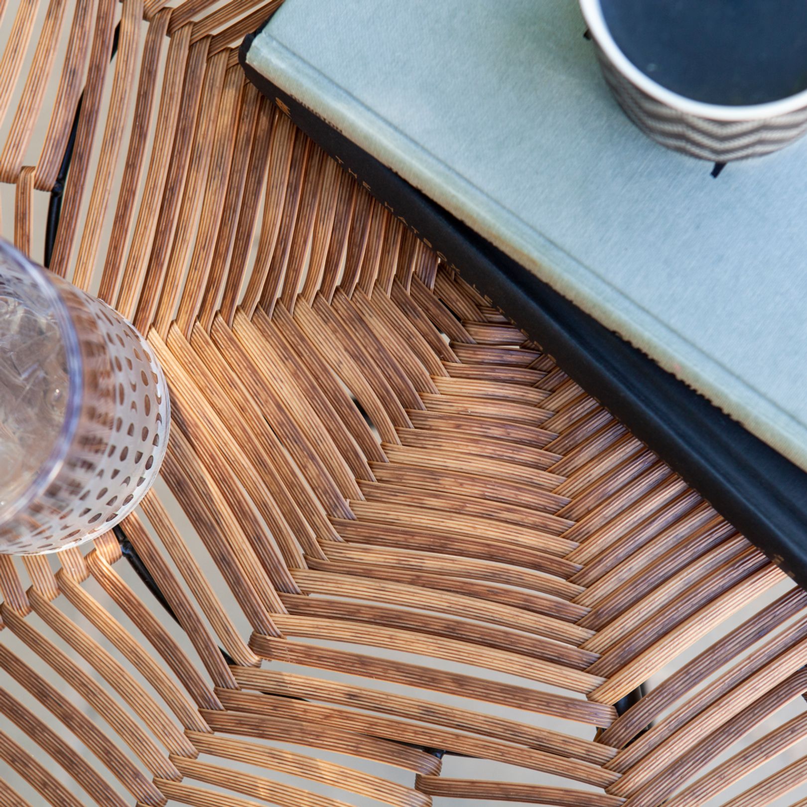 Close up photo of wicker tabletop with books and a glass