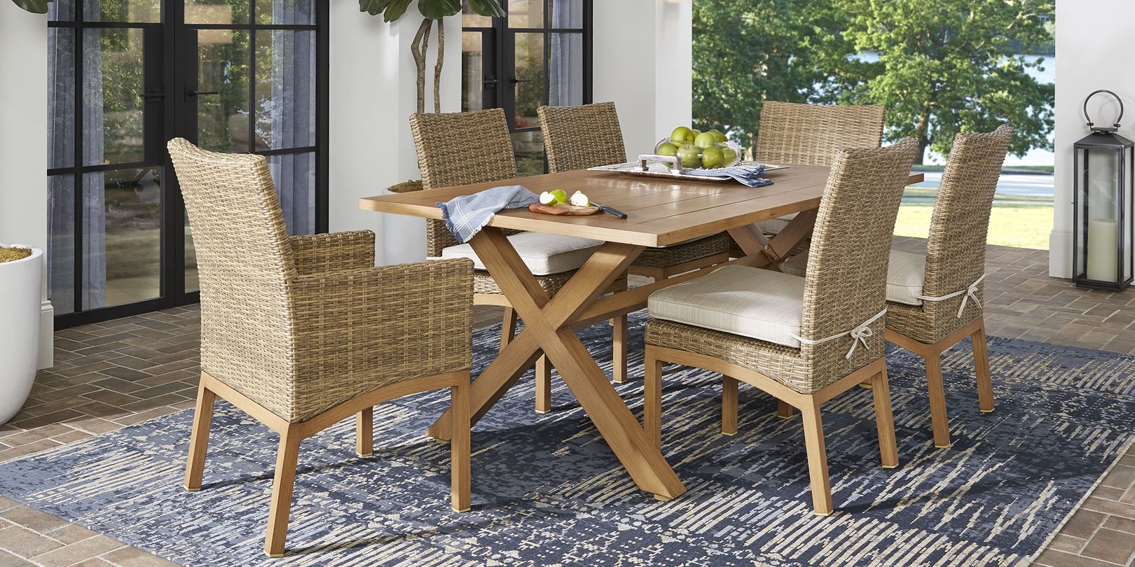 Photo of wicker and teak patio dining set with ivory cushions and blue rug