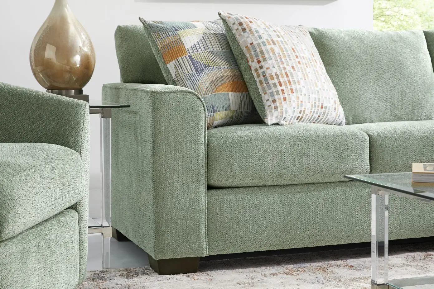Green sofa with patterned pillows.
