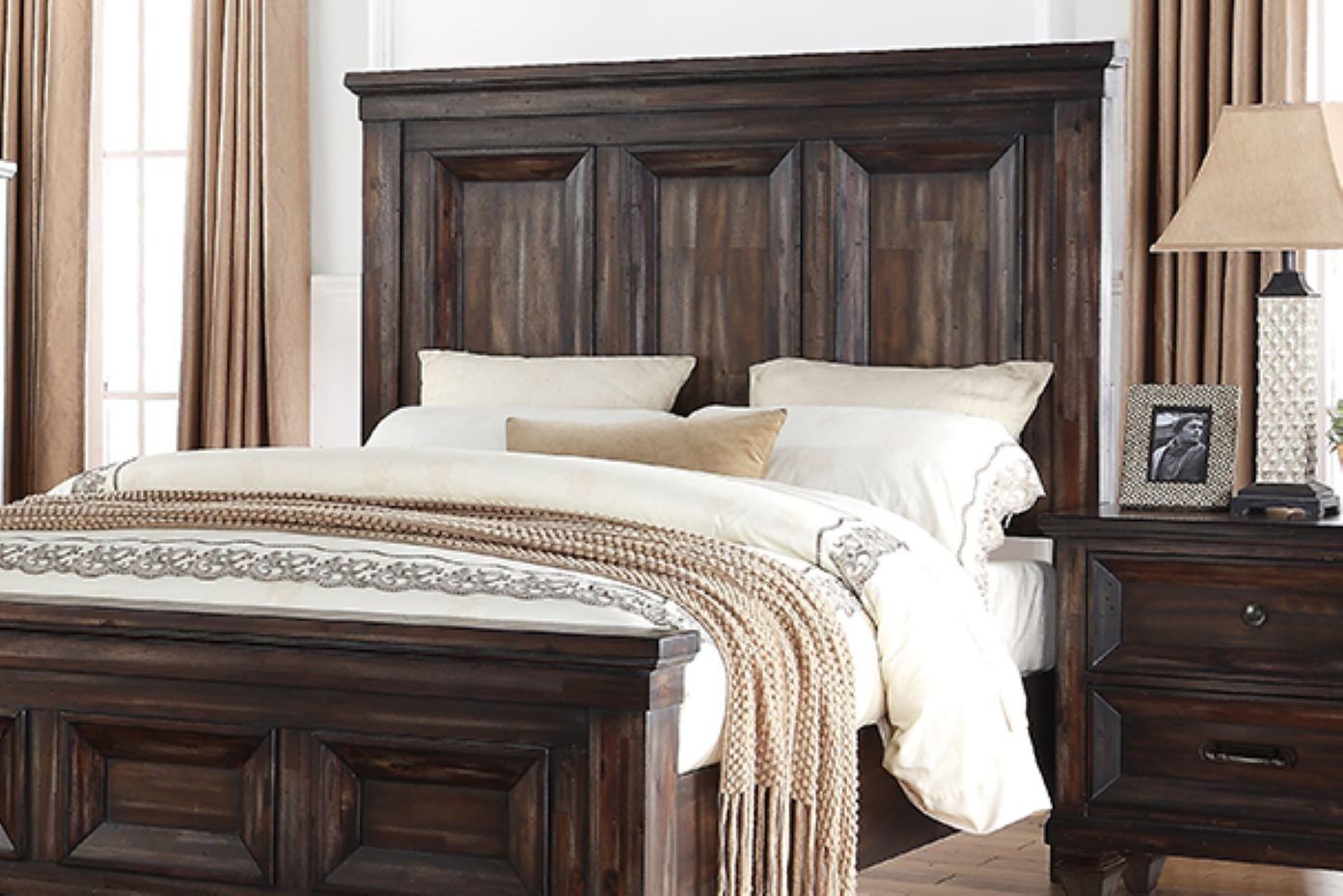 Dark wooden bed with a matching nightstand, lamp, and picture frame.
