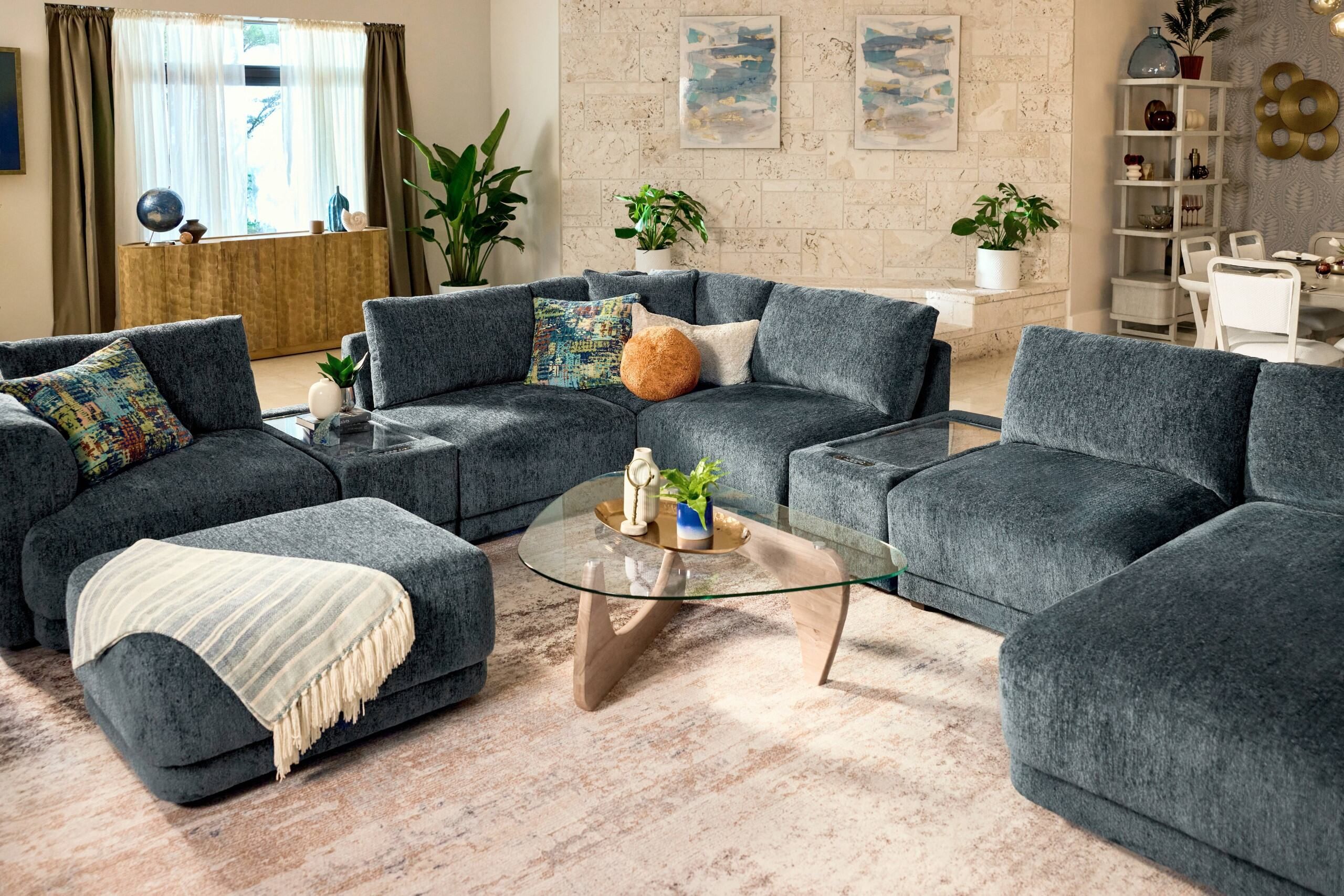 A modern sectional sofa with a glass coffee table and a patterned rug.
