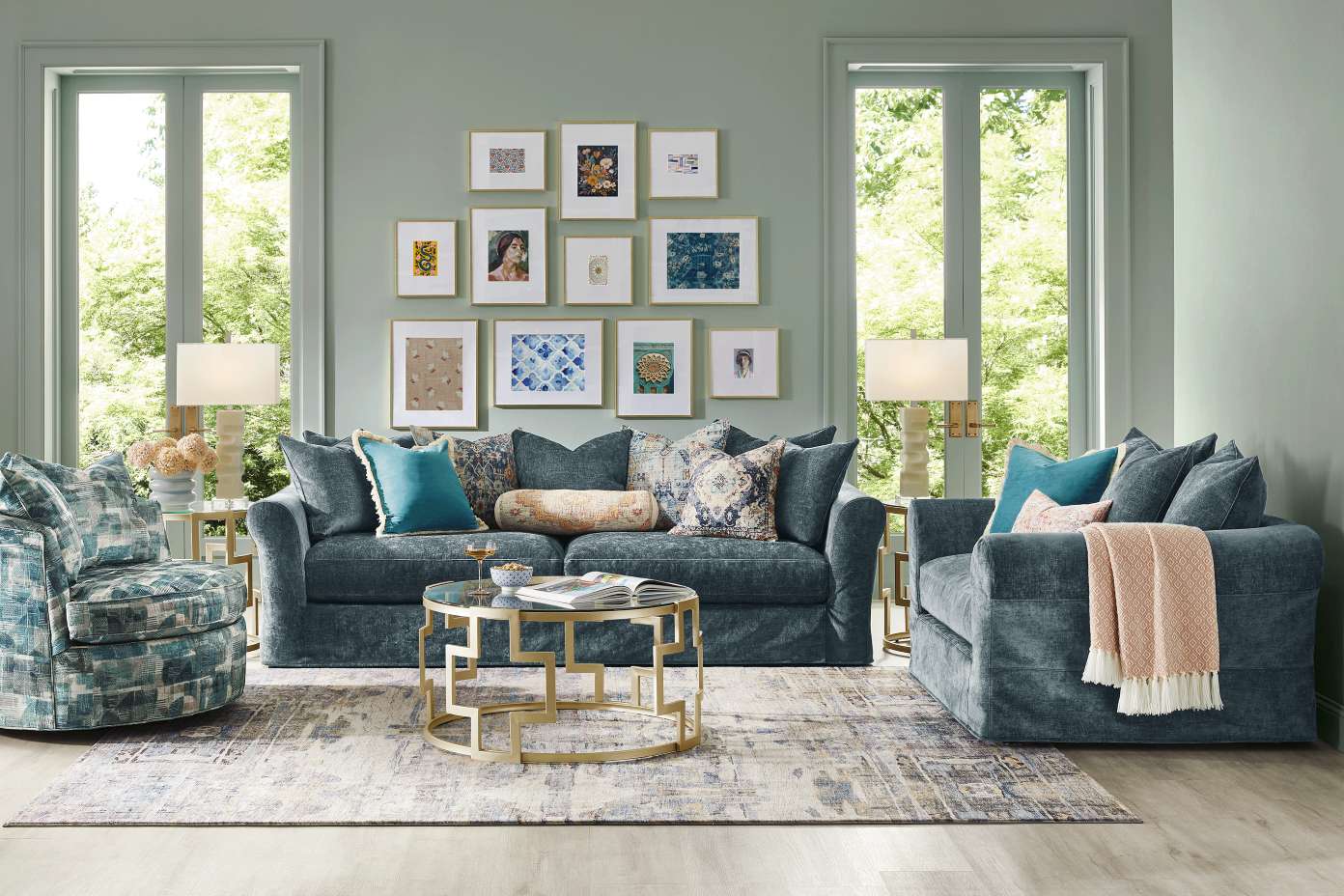 A living room with a blue sofa, armchair, and patterned rug. There are framed pictures on the wall.