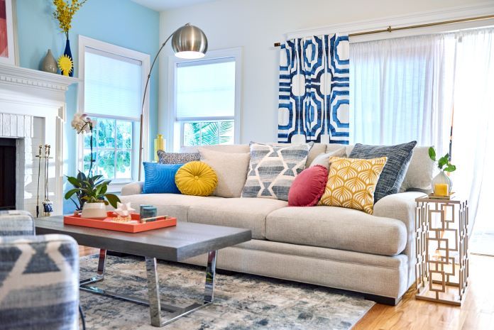 A living room with a beige sofa, colorful pillows, and a gray coffee table.
