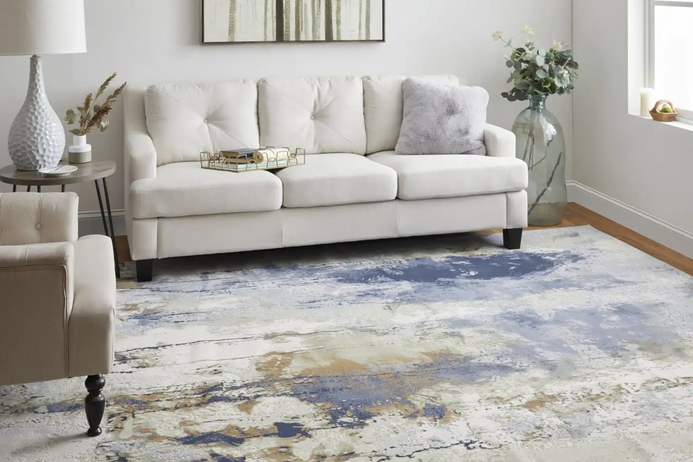 White sofa with a blue and beige abstract rug.