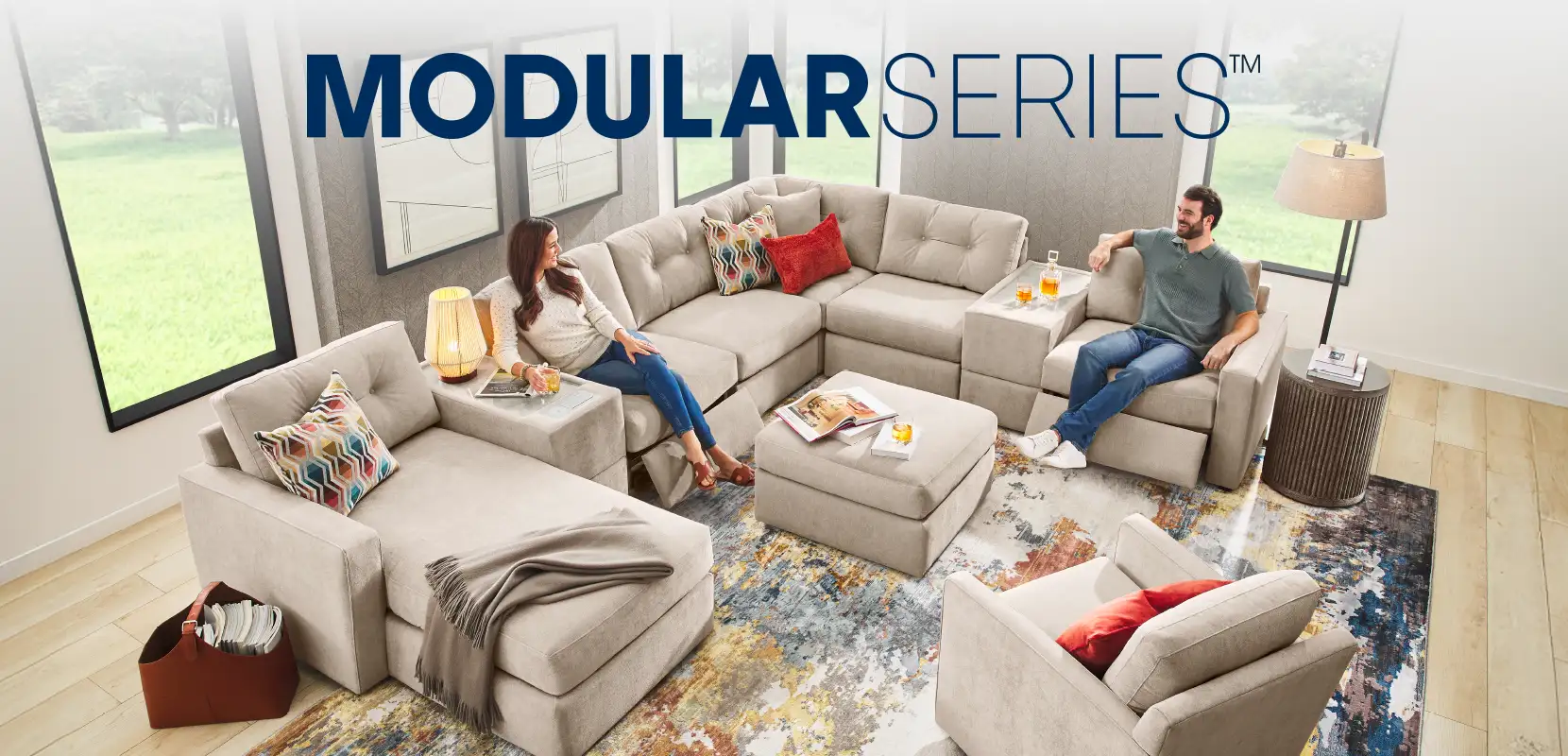 MODULAR SERIES™ A sectional sofa with a woman and a man sitting on it.
