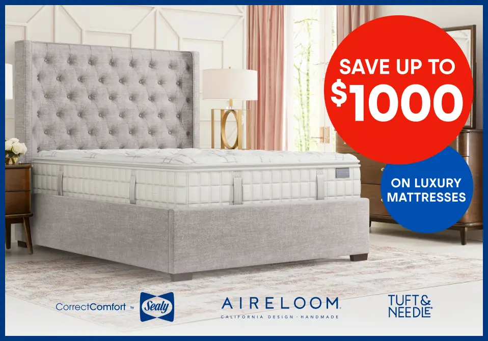 Save up to $1000 on luxury mattresses. The image shows a bed with a tufted headboard.
