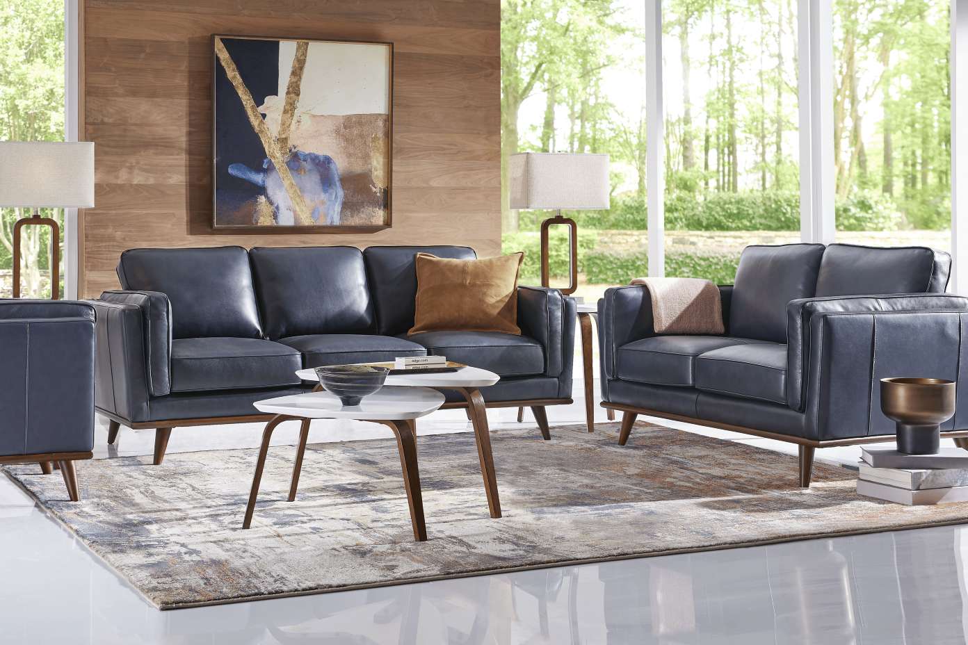 A living room with blue leather furniture, a rug, and a coffee table.
