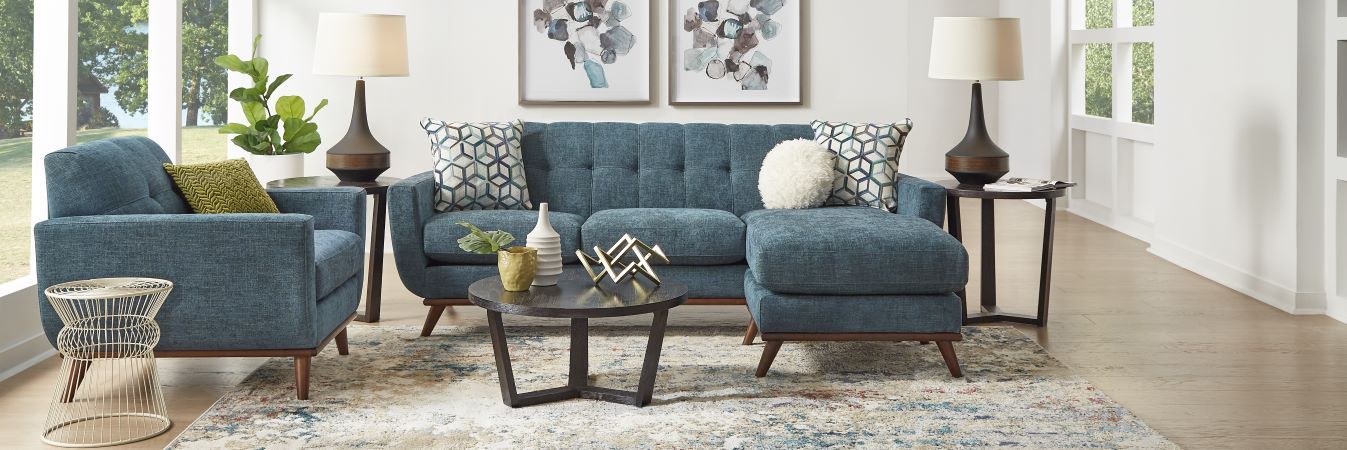 Blue sectional sofa with accent pillows, a round coffee table, and side tables with lamps.
