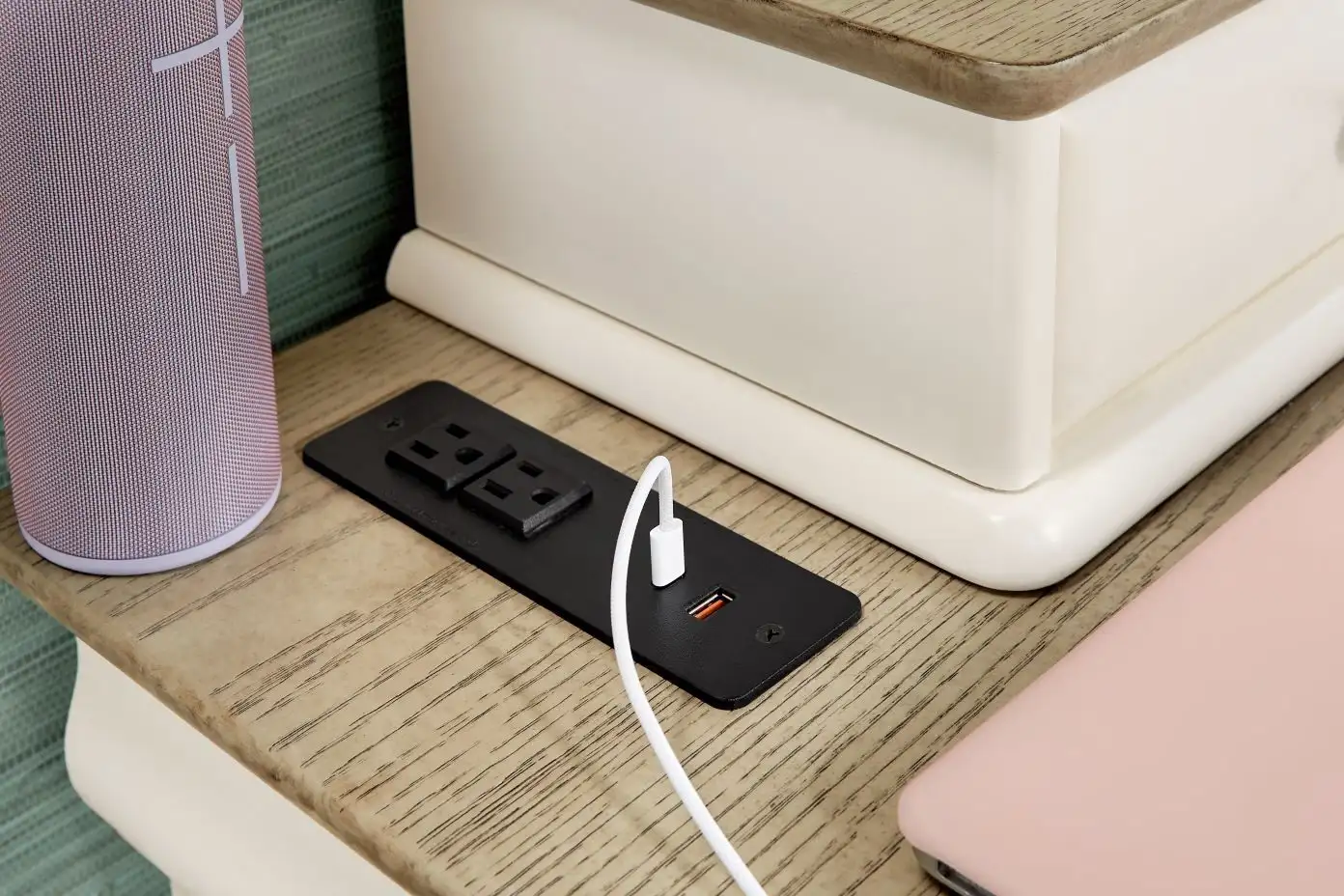 A nightstand with a built-in power outlet and USB port, a speaker, and a phone.
