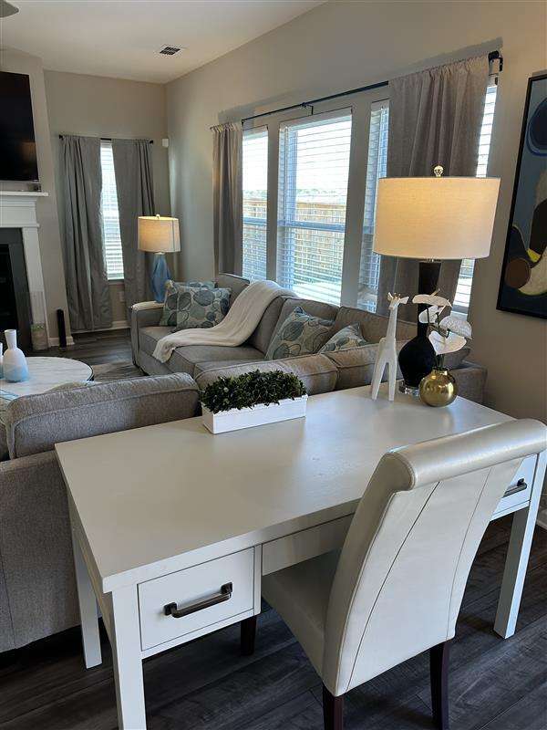 White desk and chair in a living room with a sofa and lamp.