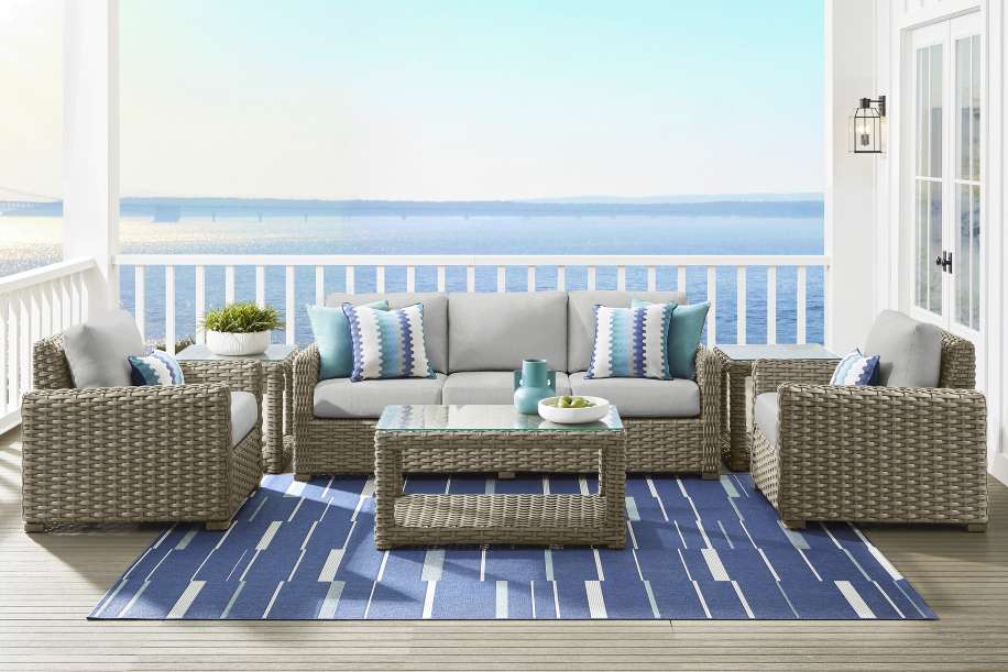 Outdoor furniture set on a deck overlooking the water.
