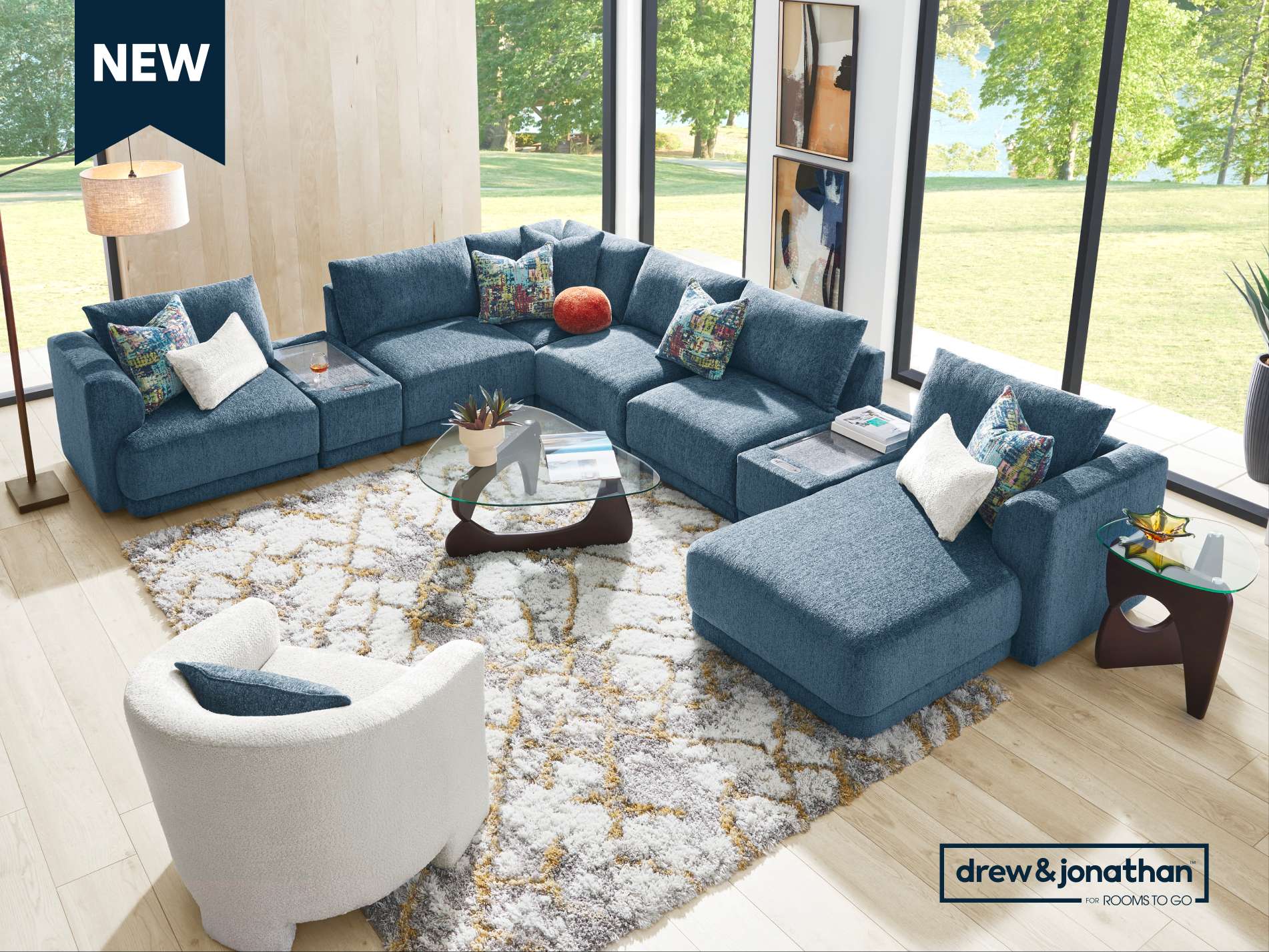 NEW. Blue sectional sofa with a white chair and a patterned rug.
