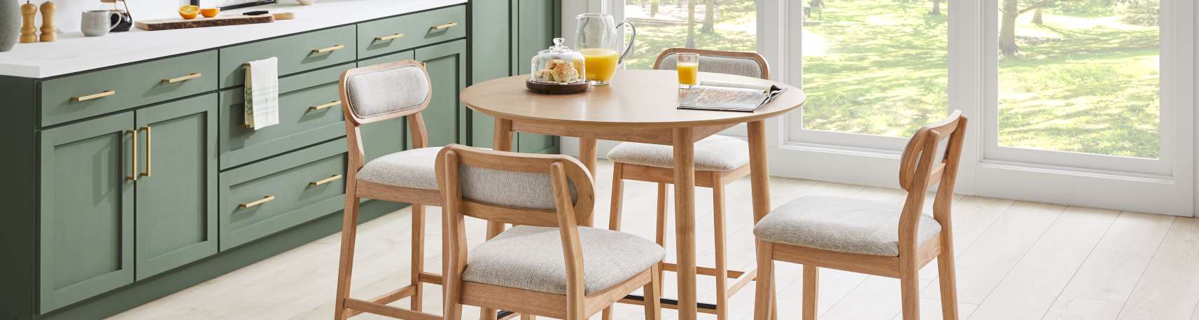 A kitchen with a round table and four chairs. The cabinets are green.
