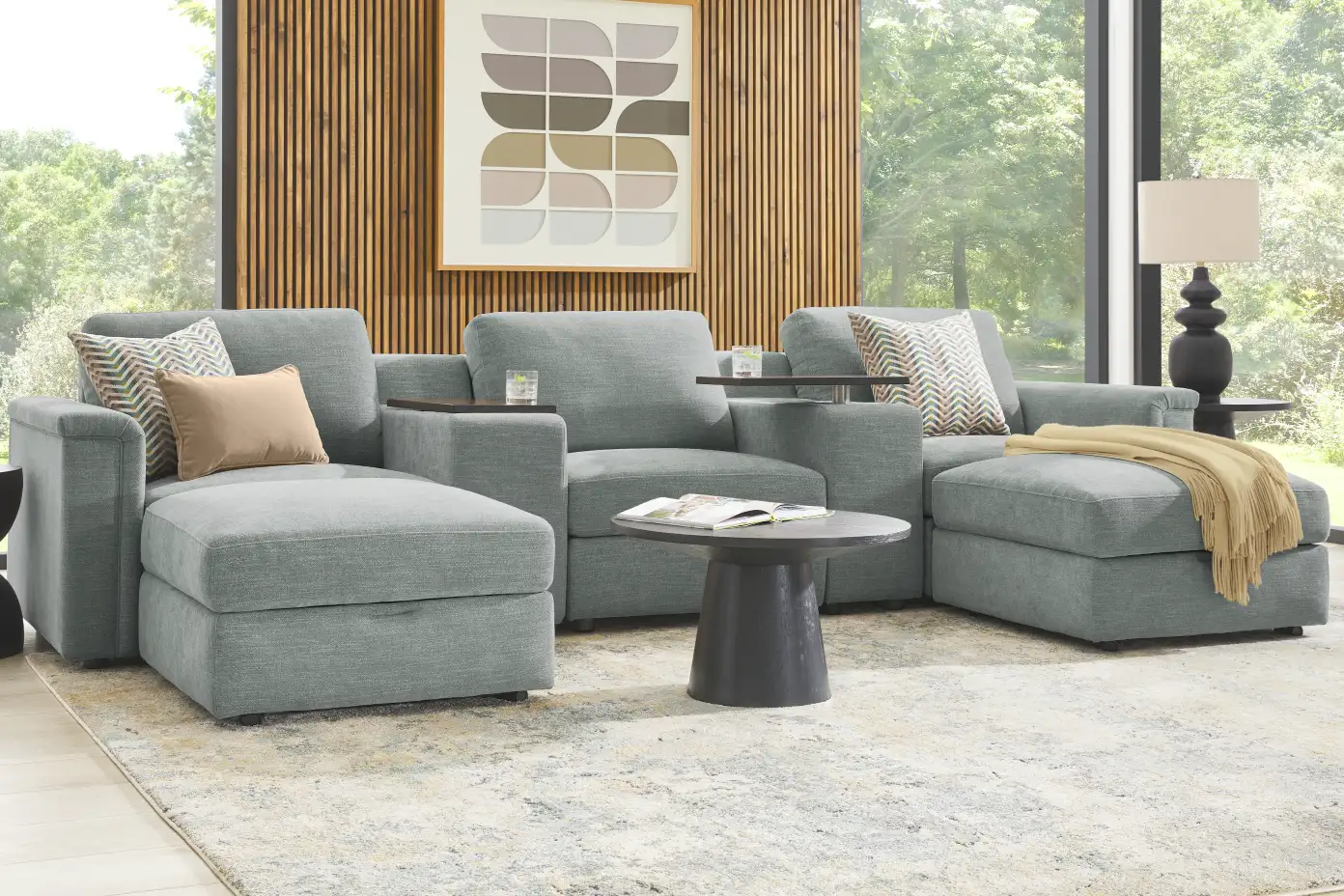Gray sectional sofa with a round coffee table and a patterned rug.
