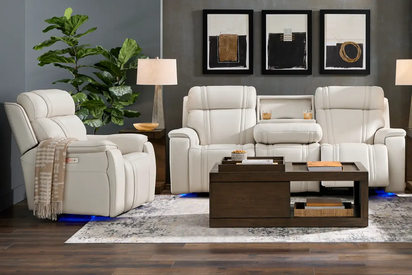 White leather recliner and sofa set with a coffee table and abstract art.