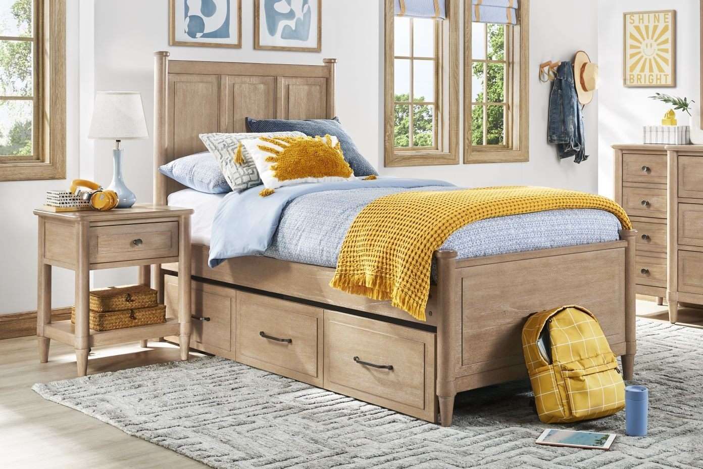 Wooden bed with storage drawers, yellow blanket, and decorative pillows.