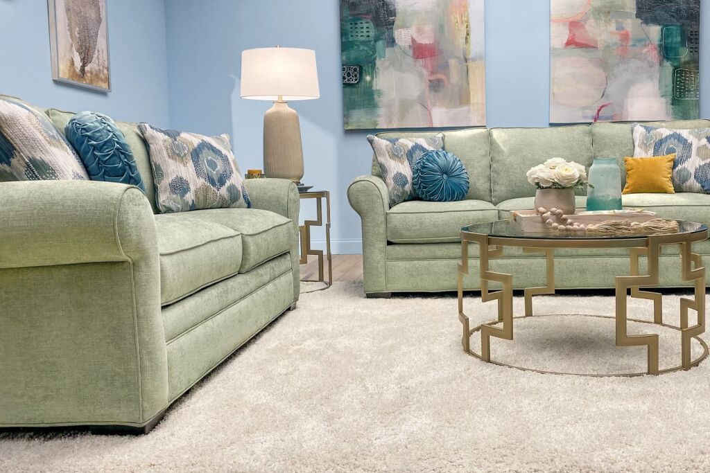Two green sofas with decorative pillows, a coffee table, and abstract art.
