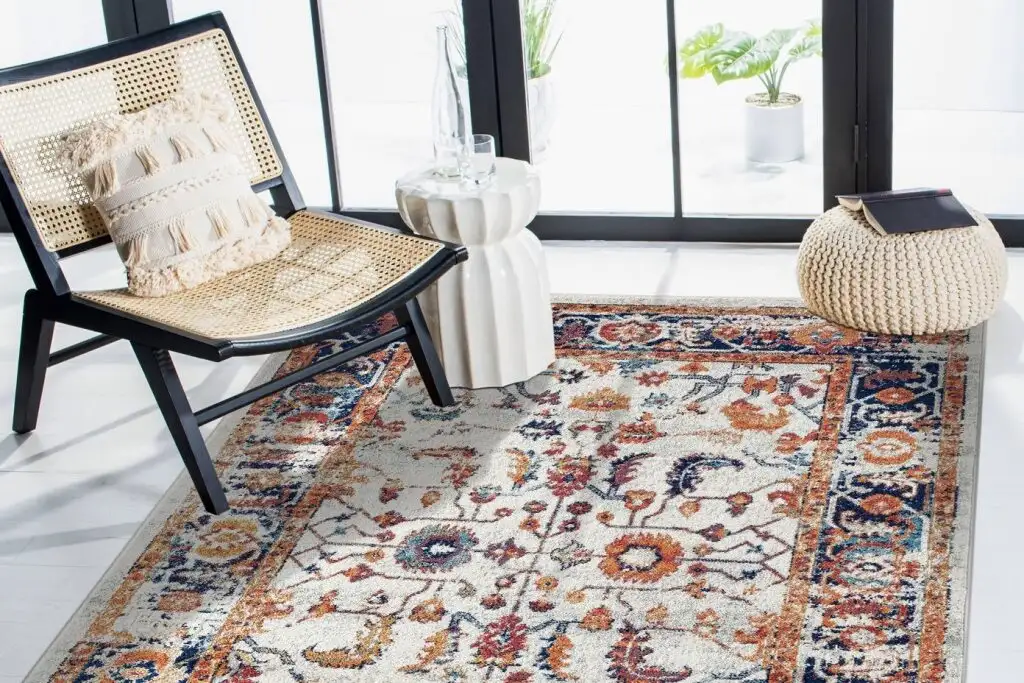 A cream-colored rug with a floral pattern, a black chair, and a white side table.