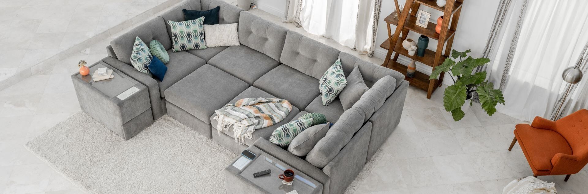 A large gray sectional sofa with decorative pillows and a throw blanket.