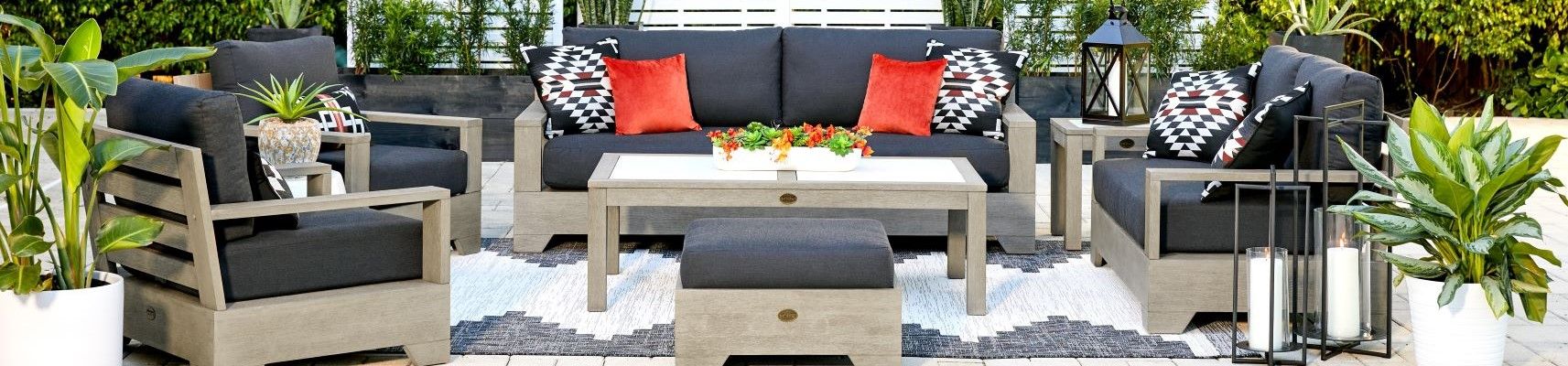 Outdoor furniture set with gray cushions and orange pillows.
