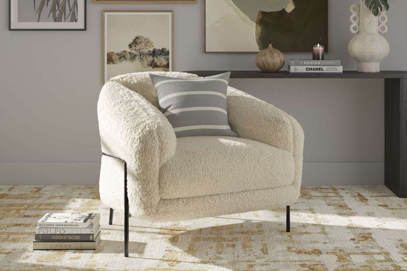 Cream-colored sherpa armchair with a striped pillow, black legs, and books on the floor.
