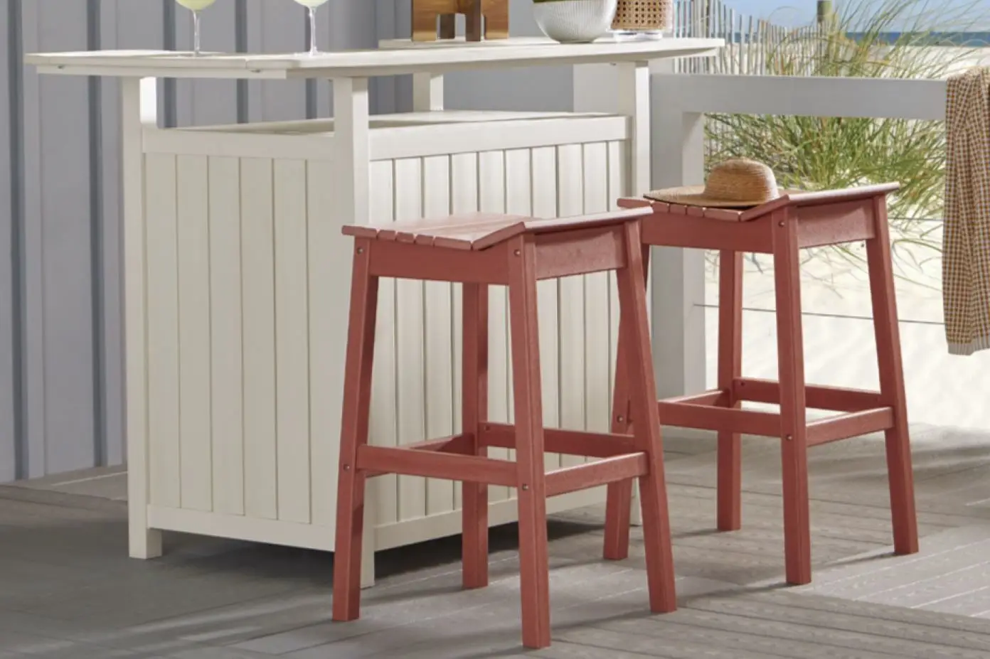 Two red bar stools in front of a white outdoor bar.
